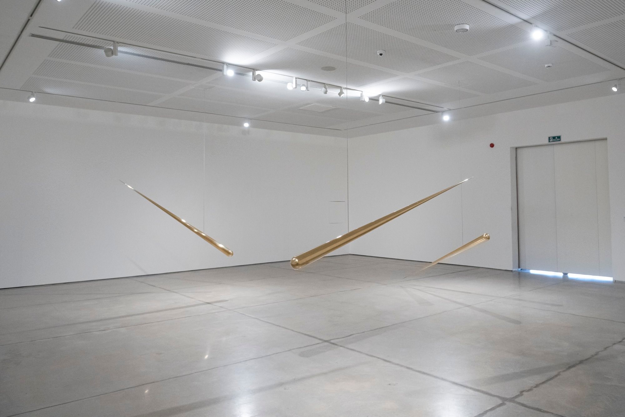 Piezas lineales metálicas de Artur Lescher apoyadas en la pared de una sala del MACA