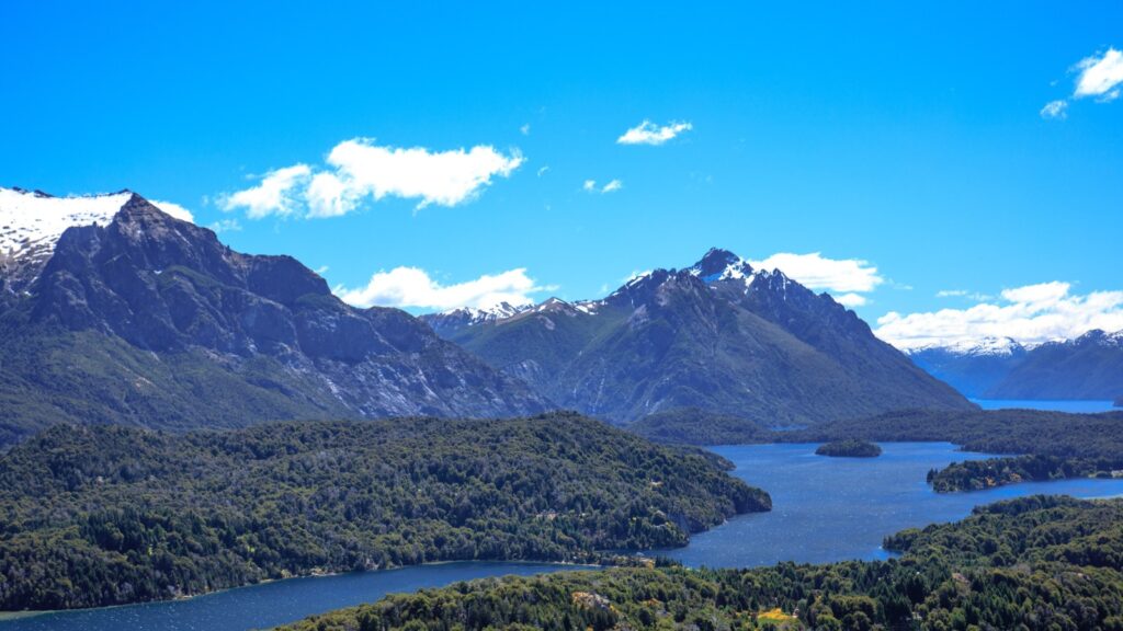 Vista aérea de Bariloche con lagos azules, bosques y cerros nevados de la cordillera
