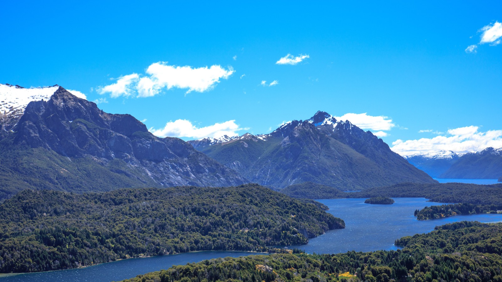 Vista aérea de Bariloche con lagos azules, bosques y cerros nevados de la cordillera
