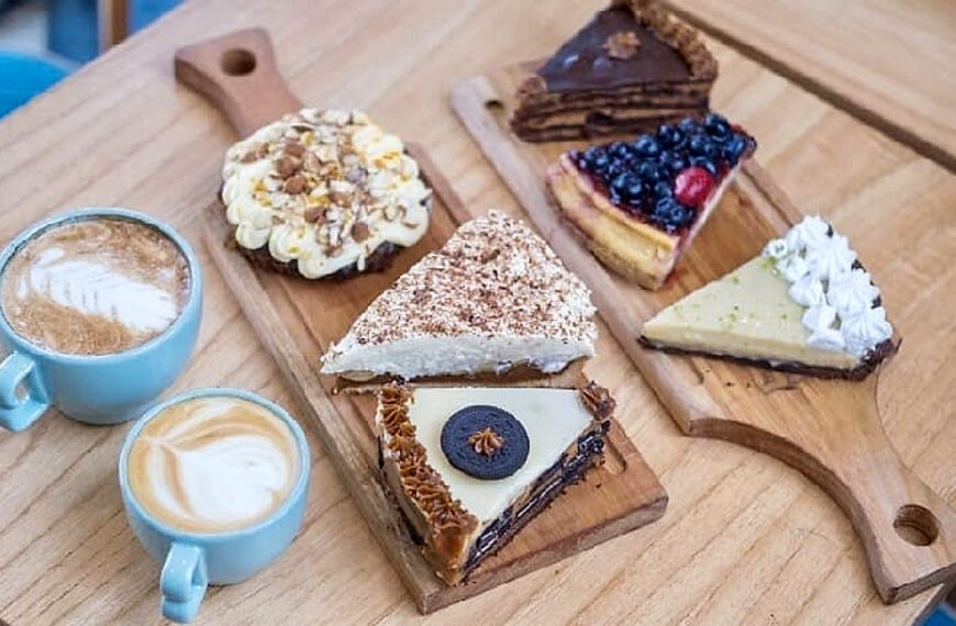 Cafés y porciones de tortas de Bilbo Café sobre una tabla de madera