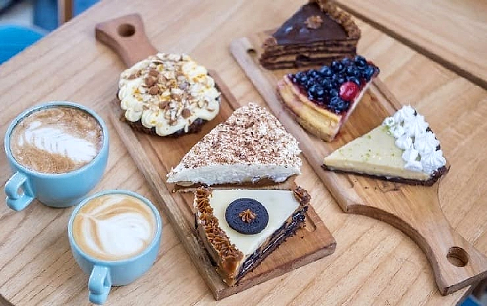 Cafés y porciones de tortas de Bilbo Café sobre una tabla de madera
