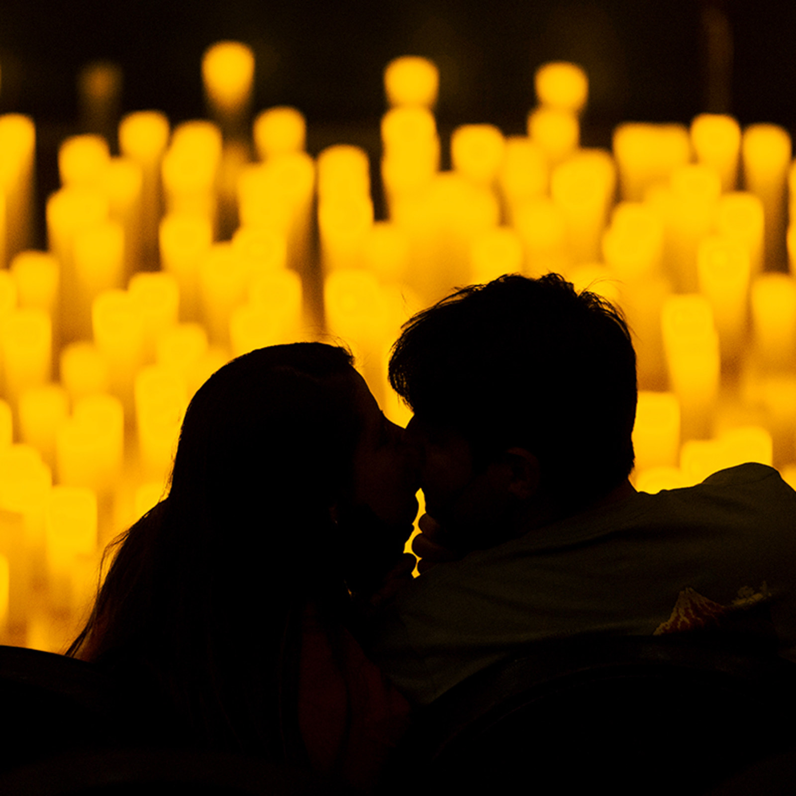 Pareja en silueta frente a un escenario cubierto de velas