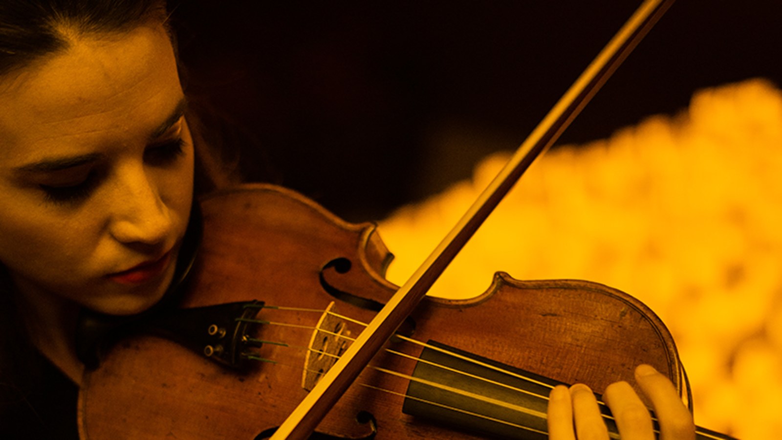 Violinista tocando en un concierto Candlelight rodeada de velas