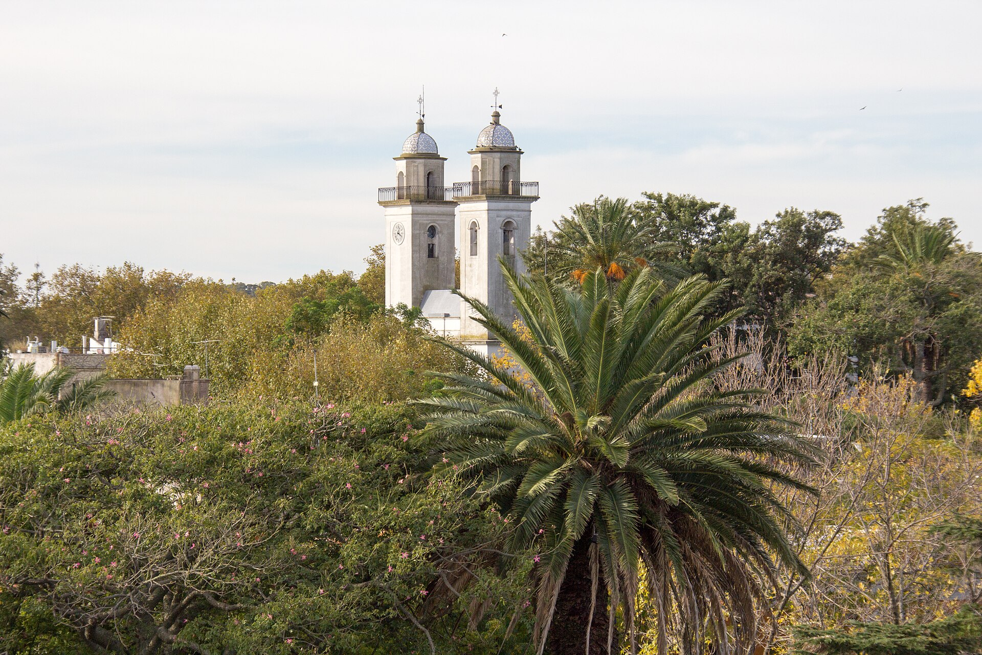 Torres de la Basílica del Santísimo Sacramento entre palmeras en Colonia del Sacramento