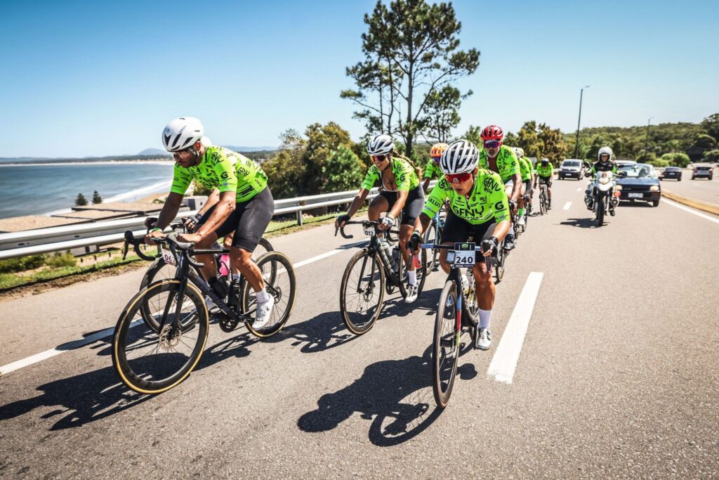 Pelotón de ciclistas del GFNY Punta del Este rodando junto al mar en un día soleado