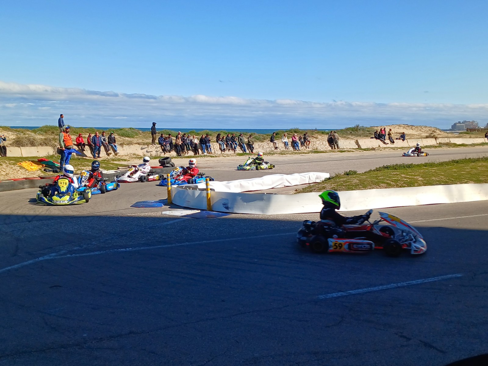 Varios karts toman una curva con público y el mar de fondo