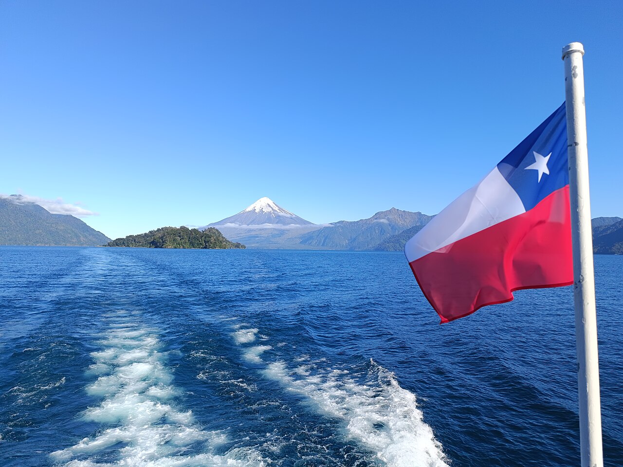 Estela de un barco en el lago Todos los Santos con bandera chilena