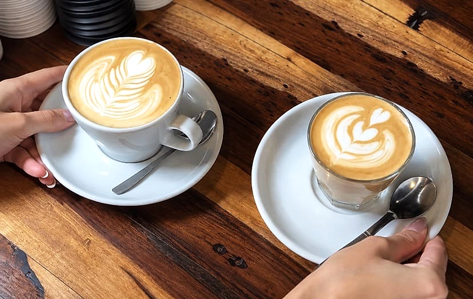 Dos tazas de café con latte art sobre una mesa de madera en LATTEnte