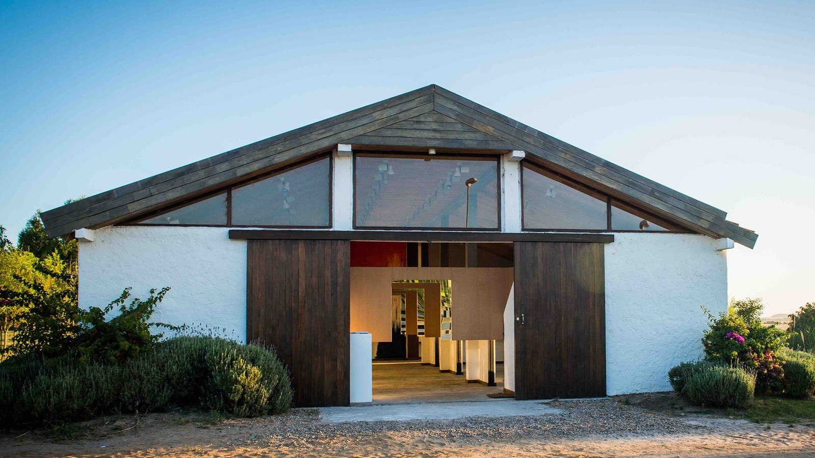 Fachada blanca con techo de madera oscura de Piero Atchugarry Gallery en Garzón