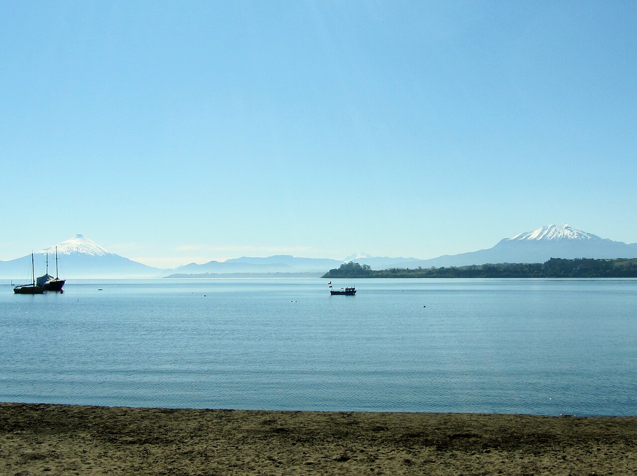 Lago Llanquihue en calma con volcanes en el horizonte