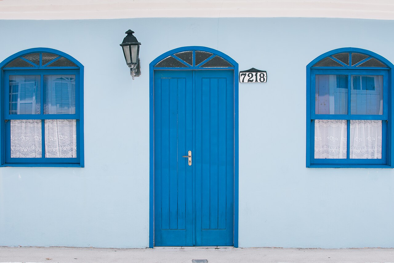 Fachada blanca con puerta y ventanas azules en Ribeirão da Ilha